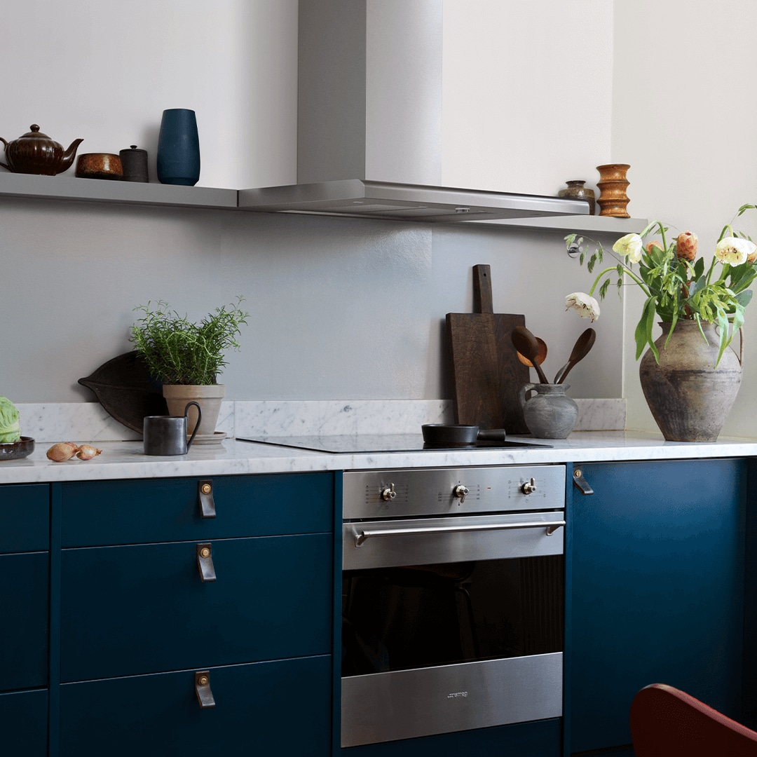 Vägghängda köksfläkten Intro i rostfritt utförande i minimalistisk köksmiljö med luckor som skapar kontrast.