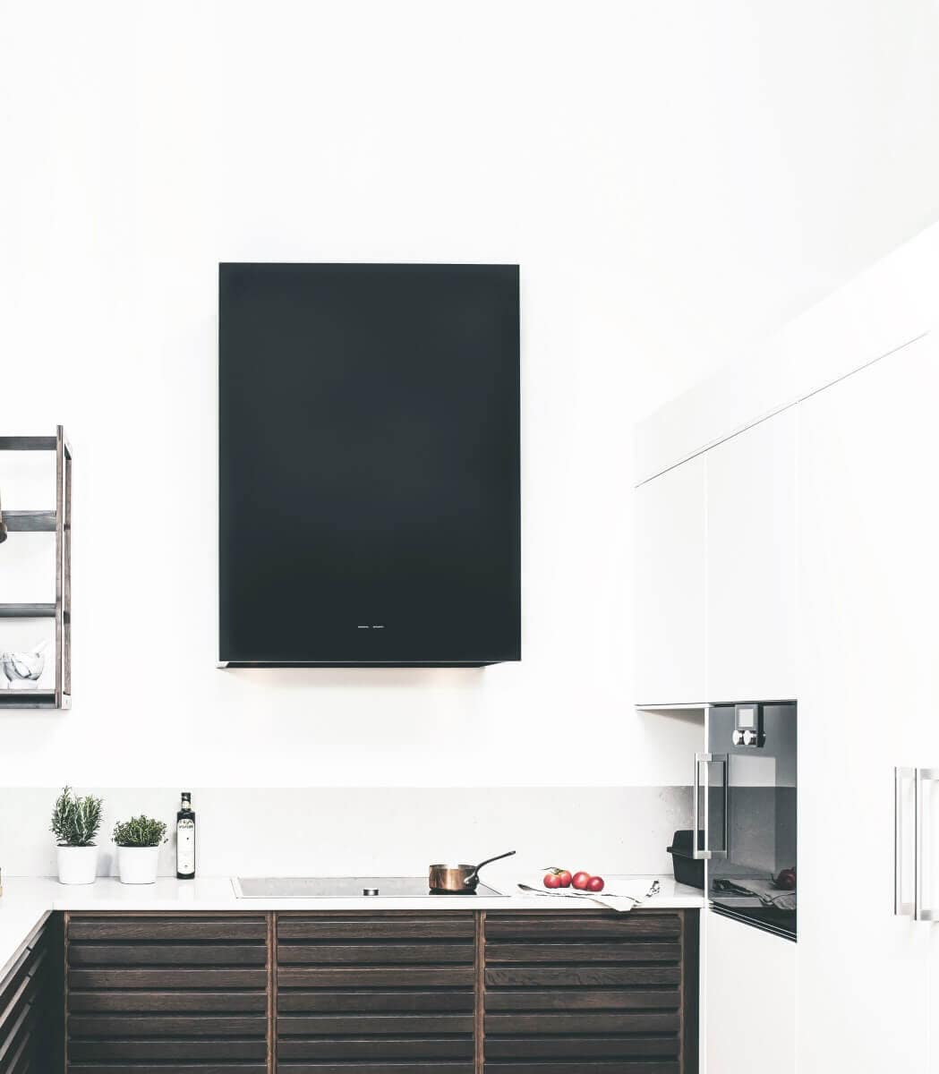 Vägghängda köksfläkten Box i svart utförande i en minimalistisk köksmiljö som skapar konstrast mellan vitt och svart.